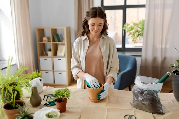 Happy woman planting pot flowers at home — Stock Photo, Image