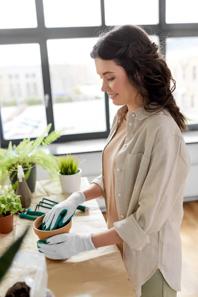 Happy woman planting pot flowers at home — Photo