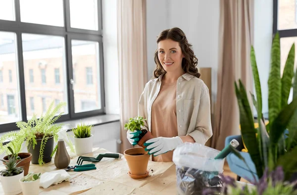 Donna felice piantare fiori in vaso a casa — Foto Stock