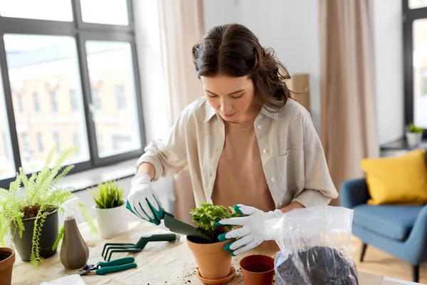 Mulher feliz plantando flores pote em casa — Fotografia de Stock