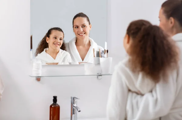 Mãe e filha olhando para espelho no banheiro — Fotografia de Stock
