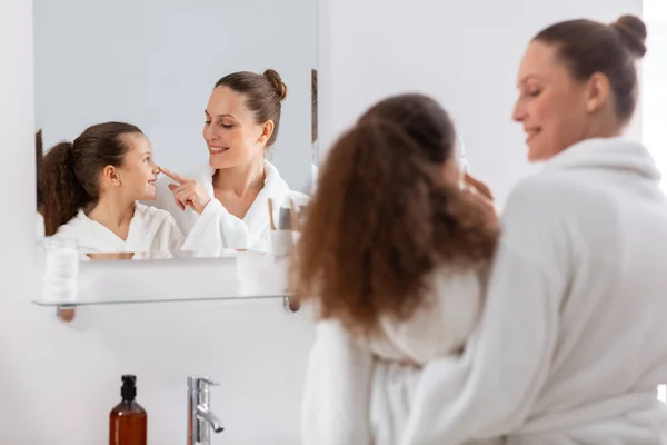 Moeder en dochter op zoek naar spiegel op badkamer — Stockfoto