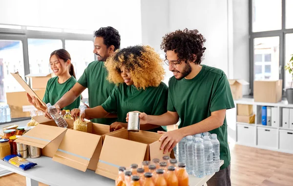 센터의 클립보드 목록에 상자에 음식을 포장하는 미소짓는 봉사자들의 — 스톡 사진