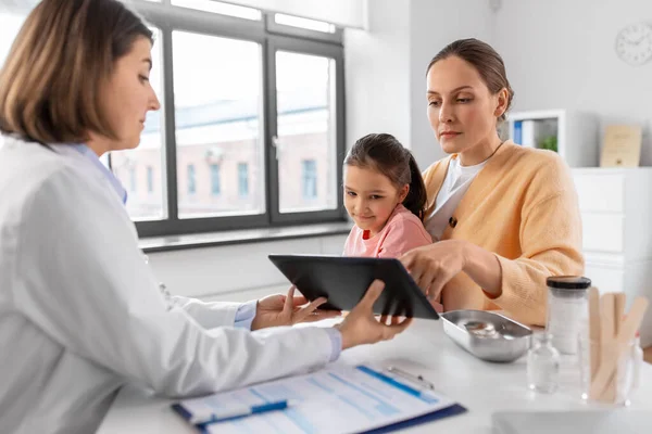 医疗保健和儿科概念 带着小女儿的母亲和医生在诊所展示平板电脑 — 图库照片