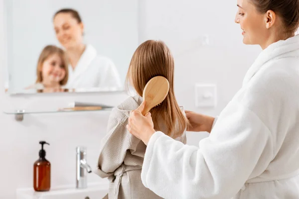 朝と人々のコンセプト バスルームでヘアブラシブラッシング髪と幸せな笑顔の母親と小さな娘 — ストック写真