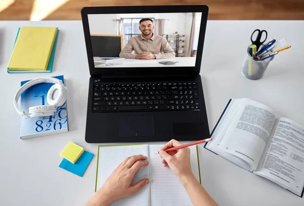 school, education and distance learning concept - female student with teacher on laptop computer screen having video call or online class at home