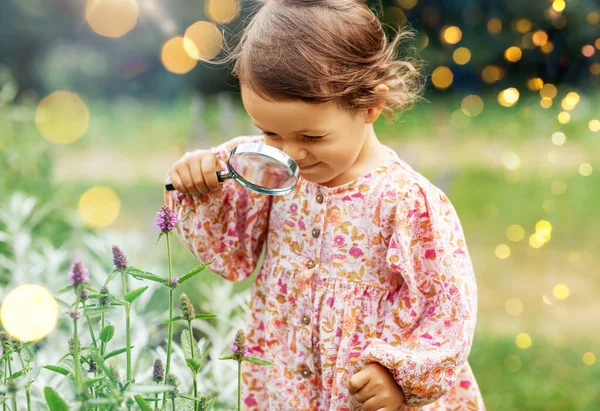 子供時代 レジャーと人々のコンセプト 夏の庭で花を見て拡大と幸せな小さな赤ちゃんの女の子 — ストック写真