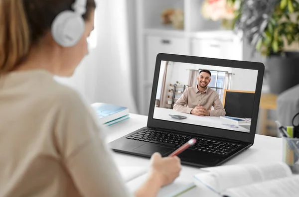 school, education and distance learning concept - happy smiling female student with teacher on laptop computer screen having video call or online class at home