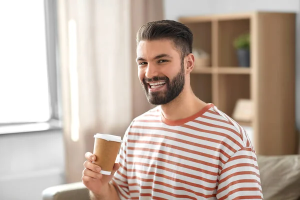 飲料と人々のコンセプト 笑顔の男は自宅で紙コップからテイクアウトコーヒーを飲む — ストック写真
