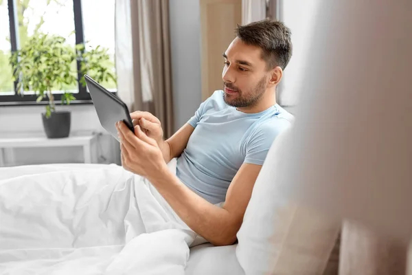 テクノロジーとインターネットと人々のコンセプト 家のベッドルームでタブレットPcコンピュータを持つ男 — ストック写真