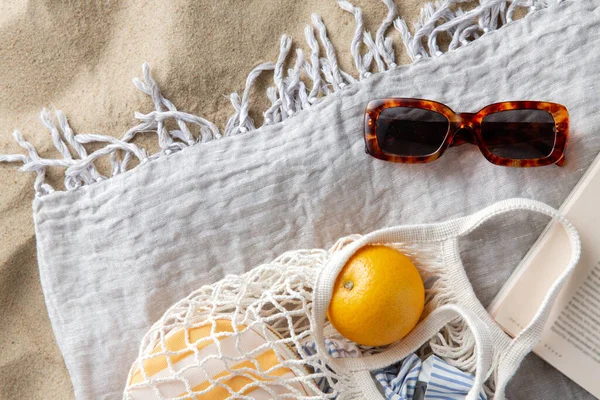 レジャーと夏休みのコンセプト ビーチの砂の上に毛布のオレンジ サングラスや雑誌の袋 — ストック写真