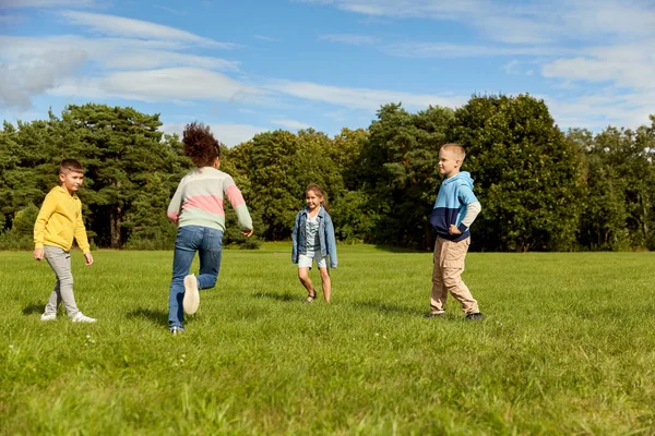 闲暇和人的概念 一群快乐的孩子玩捉迷藏游戏和在公园里跑步 免版税图库照片