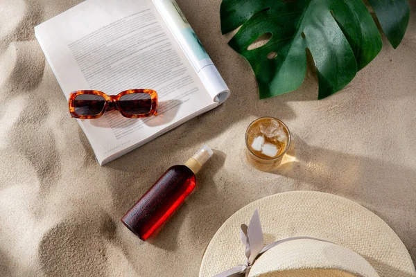 レジャーと夏休みのコンセプト オープンマガジン 日焼け止め ビーチの砂の上に氷の飲み物とサングラスのガラス — ストック写真