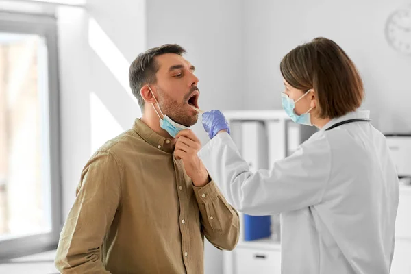 医疗保健和人的概念 戴着口罩的女医生检查住院男病人喉头酸痛 — 图库照片