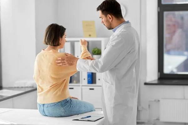 医疗保健和人的概念 男性医生 与在医院显示手臂酸痛病人的妇女对话 — 图库照片
