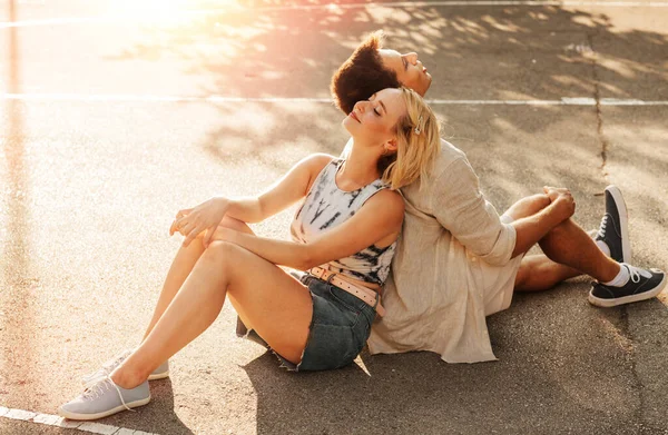 暑假与人的概念 一对快乐的年轻夫妇背靠背地坐在篮球场上 — 图库照片