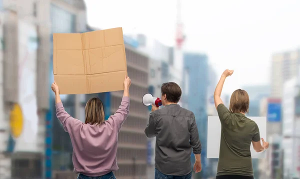 protest and human rights concept - group of people with poster and megaphone protesting on demonstration over city background