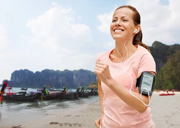 运动和健康的生活方式概念 在法属波利尼西亚 带着耳机的笑着女人 戴着智能手机臂章 在热带海滩边听音乐 — 图库照片