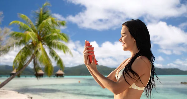 晒和美容美感 身穿比基尼泳衣的快乐的年轻女性在法属波利尼西亚热带海滩的背景上喷涂防晒霜 — 图库照片