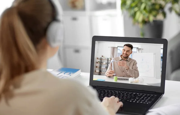 school, education and distance learning concept - happy smiling female student with teacher on laptop computer screen having video call or online class at home