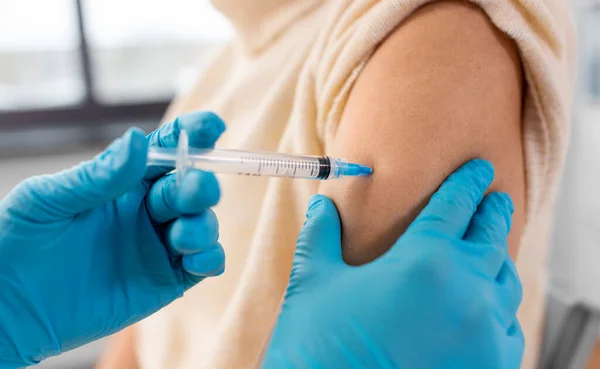 健康和疫苗接种概念 在医院为妇女提供注射器 疫苗或药物注射 使医生或护士关门 — 图库照片