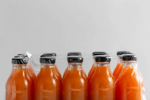 storage, drinks and packaging concept - close up of pack of glass bottles with fruit or vegetable juice on grey background