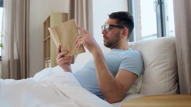 Conceito Pessoas Descanso Homem Óculos Livro Leitura Cama Casa — Vídeo de Stock