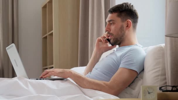 技术和远程工作概念 带文件夹和手提电脑的人在家里卧室的床上用智能手机打电话 — 图库视频影像