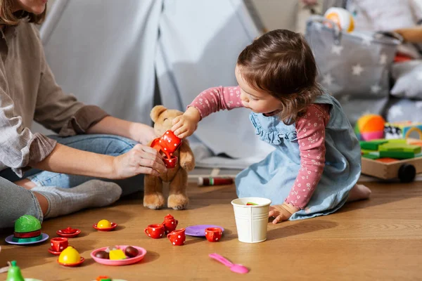 レジャー 人々のコンセプト 幸せな母親と小さな赤ちゃんの娘は自宅でおもちゃの料理のセットでティーパーティーをプレイ — ストック写真