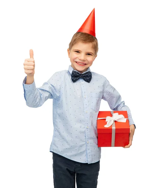 誕生日 子供時代 人々の概念 白い背景に親指を示すギフトボックスとパーティーの帽子の笑顔の男の子の肖像画 — ストック写真