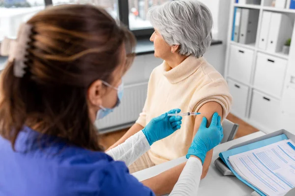 健康及防疫注射概念 医生或护士在医院为戴口罩的老年妇女注射注射器 疫苗或药物 — 图库照片