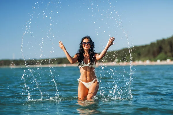 夏天和泳装的概念 身穿比基尼泳衣的快乐微笑的女人在海滩上泼洒海水 — 图库照片