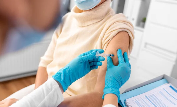 병원에서 마스크를 나이든 여성에게 백신이나 주사를 제조하는 의사나 간호사를 가까이 — 스톡 사진