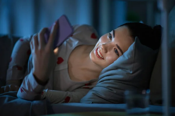 Technológia Lefekvés Pihenés Koncepció Boldog Mosolygós Tini Lány Pizsamában Okostelefonnal — Stock Fotó
