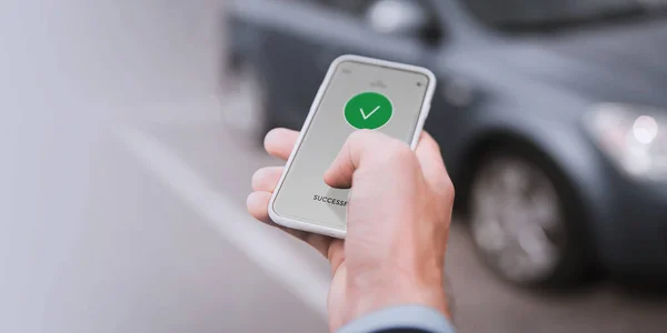 carsharing, transportation and technology concept - close up of hand with on smartphone screen over car on background