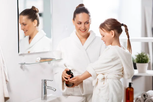 朝と人々のコンセプト バスルームに液体石鹸で幸せな笑顔の母親と小さな娘 — ストック写真