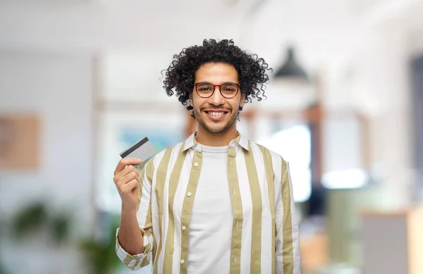 shopping, finance and people concept - happy smiling man with credit card over office background