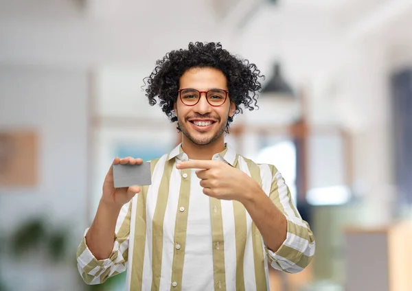 shopping, finance and people concept - happy smiling man with credit card over office background