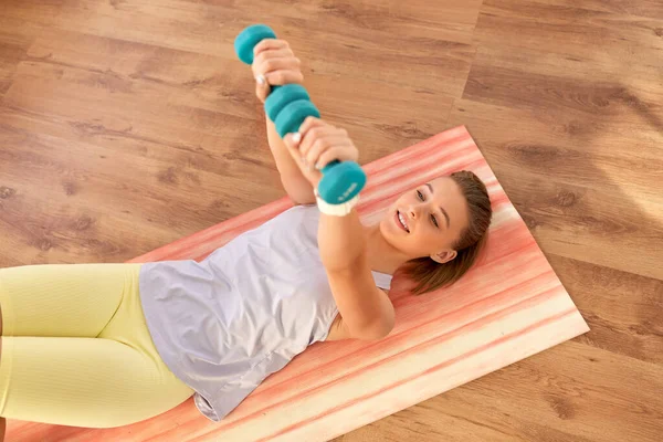 运动和健康的生活方式概念 快乐的少女 带着哑铃在家里瑜伽垫上锻炼 — 图库照片