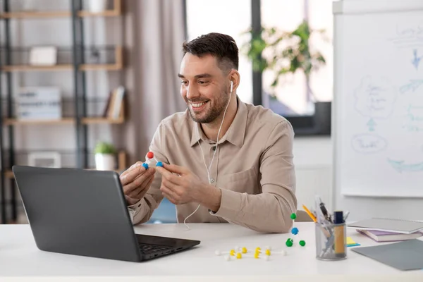 distance education, school and remote job concept - happy smiling male chemistry teacher with laptop computer and molecular model having online class at home office