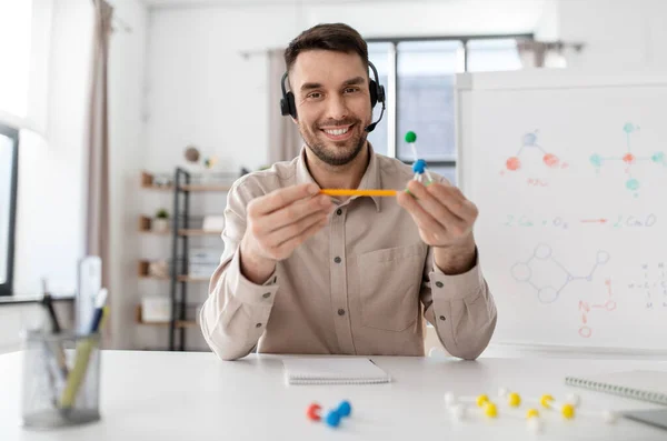 distance education, school and remote job concept - happy smiling male chemistry teacher in headset with molecular model having online class at home office