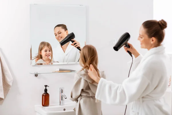 朝と人々のコンセプト バスルームでヘアドライヤーと幸せな笑顔の母親と小さな娘 — ストック写真