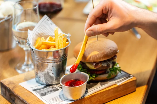 fast food, unhealthy eating and people concept - close up of hand dipping french fries to ketchup at restaurant