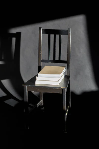 interior and home decor concept - books on vintage chair on black background