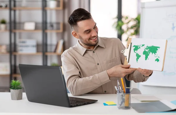 distance education, school and remote job concept - happy smiling male geography teacher with world map and laptop computer having online geography class at home office