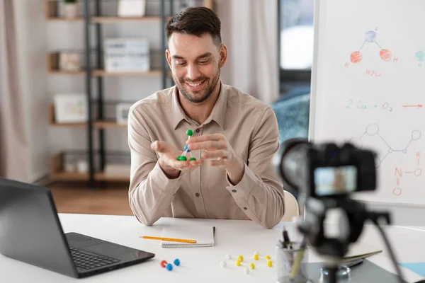 distance education, school and video blogging concept - happy smiling male chemistry teacher with camera and molecule model having online class at home office