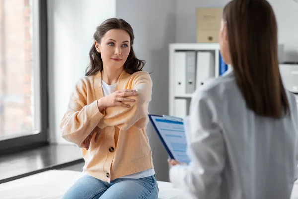 医疗保健和人的概念 在医院与显示手臂酸痛病人的妇女交谈的女医生 — 图库照片