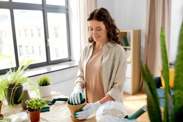 园艺和家务活概念 戴着手套在家里种植盆栽花的快乐女人 — 图库照片