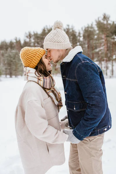 people, love and leisure concept - happy man kissing womans nose in winter forest
