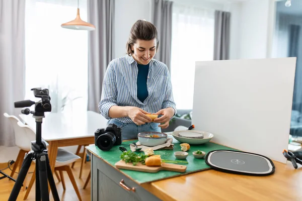 摄影和人们的观念 快乐地微笑着的女性食品摄影师 带着相机在家里厨房里布置作文 — 图库照片